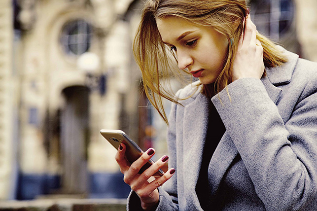 Angry and sad young woman looking at cell phone seeing bad text message, email.